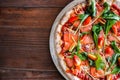 Delicious pizza on top view. Yummy pizza with tomatoes, vegetables, cheese and smoke salmon on wooden table at pizzeria. ItÃ¢â¬â¢Ãâ¬Ãâ¢